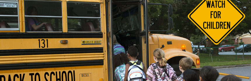 Children standing in the line and getting into the school bus